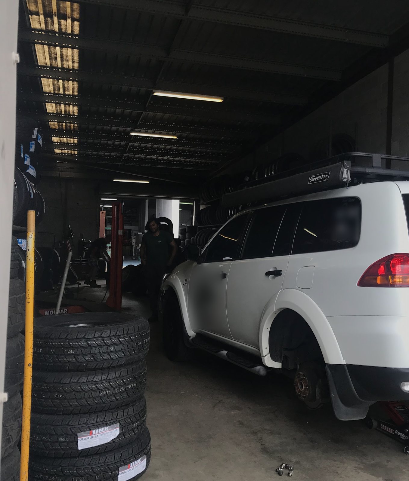 White four wheel drive in the workshop bay with tyre stock racked along the wall
